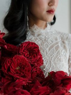 a woman in white dress holding red flowers