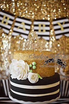 a black and white striped cake with flowers on the top is surrounded by gold sequins