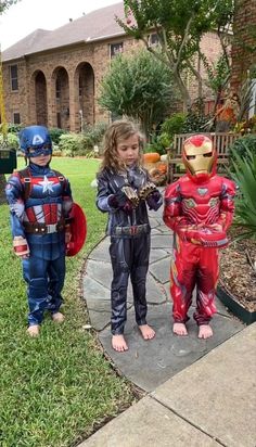 two children dressed as superheros standing in front of a house