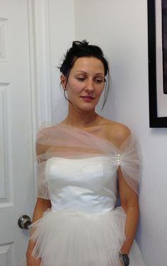 a woman in a white wedding dress standing next to a door with her hands on her hips