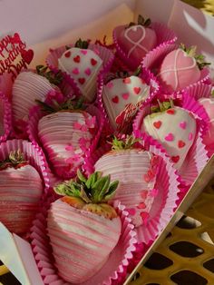 a box filled with lots of pink and white chocolate covered strawberries on top of a table