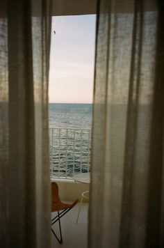 a chair sitting in front of a window overlooking the ocean