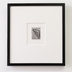 a black and white photo hanging on the wall next to a framed object with a piece of paper in it