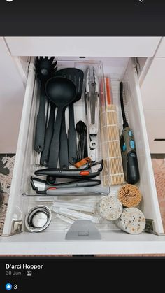 an open drawer with utensils and other kitchen items