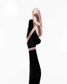 a woman's hand holding up a pair of ballet shoes that are tied together