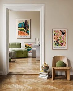 a living room filled with furniture and paintings on the wall next to a wooden floor