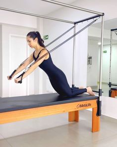 a woman in a black leotard doing pivots on a gym bench