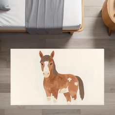 a brown and white horse standing on top of a wooden floor next to a bed