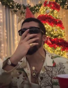 a man wearing sunglasses is taking a selfie in front of a christmas tree