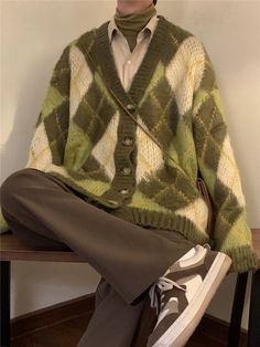 a man sitting on top of a wooden bench wearing a green and white sweater