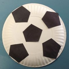 a paper plate with black and white soccer balls on the top, sitting on a blue surface