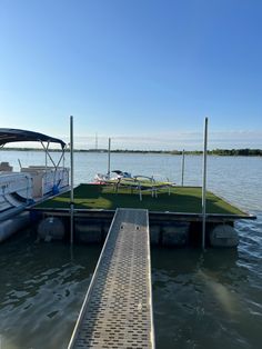 a boat docked at the end of a dock with grass on it's platform