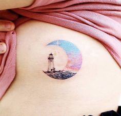 a woman's stomach with a lighthouse tattoo on it