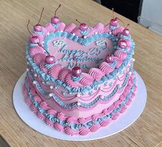 a pink and blue heart shaped cake sitting on top of a wooden table