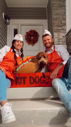 a man and woman sitting on the steps with a dog in a hot dog costume