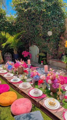 an outdoor table set up with plates and flowers