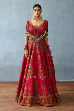 Red attached cancan lehenga with floral print and side pompom tassels. Paired with a fringed blouse with dangling cowrie shell details. - Aza Fashions Red Bohemian Lehenga With Resham Embroidery, Bohemian Red Floor-length Lehenga, Red Bohemian Lehenga With Traditional Drape, Bohemian Red Lehenga With Traditional Drape, Bohemian Embroidered Red Lehenga, Red Fitted Bohemian Sharara, Fitted Red Bohemian Sharara, Red Dresses For Reception And Navratri, Red Bohemian Floor-length Set