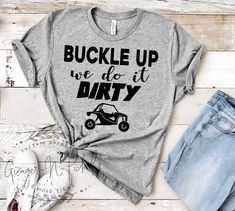 Custom made to order BUCKLE UP WE DO IT DIRTY (with RZR) unisex style t-shirt. (Please message me if you would like to change the RZR to a jeep, dirt bike or other image.) Photo shows Matte Black Design on an Athletic Grey Short Sleeve Tee. Choose from short sleeve or long sleeve tees. (Not all colors may be available in long sleeve. Please see color chart for long sleeve colors.) These soft and comfy Bella + Canvas shirts are high quality unisex shirts. The adult shirts are unisex sizing with a Riding Shirts, Buffalo Plaid Flannel, Cute Shirt Designs, Comfy Shirts, Adulting Shirts, Can Am, Plaid Flannel Shirt, Side By Side, Unisex Shirts