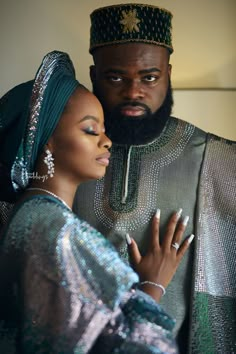 a man and woman dressed in traditional african garb embracing each other with their arms around one another