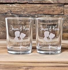 two personalized shot glasses sitting on top of a wooden table