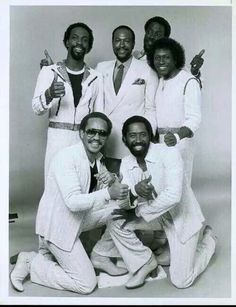 a group of men in white suits posing for a photo