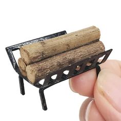 a small piece of wood sitting on top of a metal stand with a hand holding it