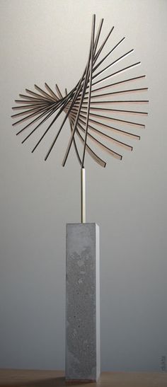 a sculpture made out of sticks on top of a wooden table next to a wall