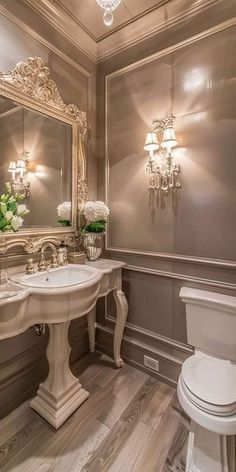 a white toilet sitting next to a sink in a bathroom under a chandelier