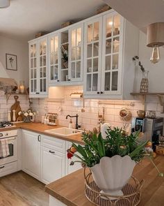 a kitchen filled with lots of white cabinets and wooden counter top space next to an oven