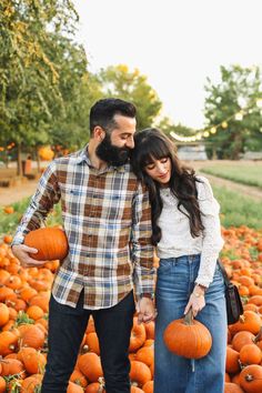 a man and woman holding pumpkins in a field