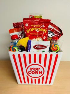 a popcorn box filled with candy and candies sitting on top of a wooden table