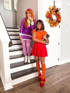 two women dressed in halloween costumes standing on stairs