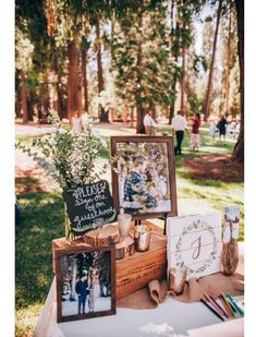 a table with pictures and other items on it in the grass at a wedding reception