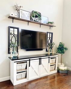 a living room with white furniture and a flat screen tv on top of a entertainment center