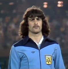 a man with long hair wearing a blue jacket