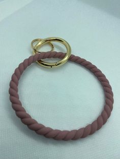 two gold rings sitting on top of a pink rope