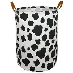 a black and white cow print laundry hamper with two wooden handles on the side