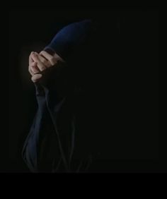 the man is covering his face with his hands while standing in front of a black background