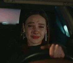 a woman sitting in the passenger seat of a car with her eyes closed and one hand on the steering wheel