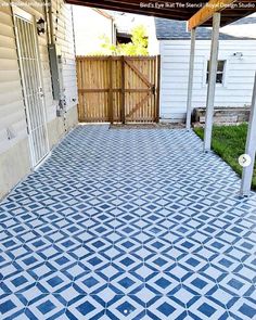 an outdoor patio with blue and white tiles on the ground, in front of a house