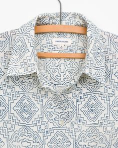 a white and blue patterned shirt hanging on a hanger