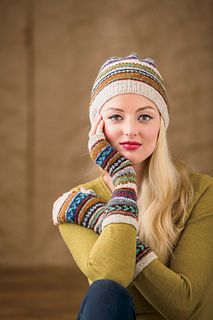 a woman sitting on the floor with her hands under her face wearing knitted mittens