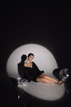 a woman sitting on the ground in front of a black and white background with bubbles