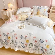 a bed with white and yellow flowers on the comforter, pillows and pillow cases