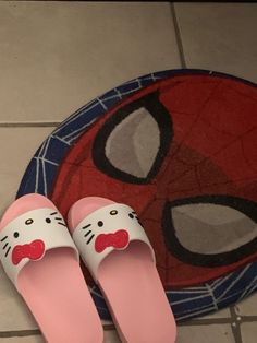 a pair of hello kitty slippers sitting on top of a floor next to a spider man rug