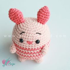 a crocheted stuffed animal with pink ears and nose sitting on a white surface