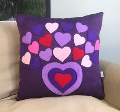 a purple pillow with hearts on it sitting on a couch