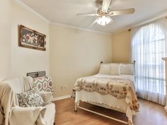 a bed sitting next to a white couch in a bedroom on top of a hard wood floor