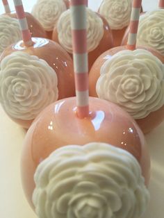 there are many candy apples with pink and white striped straws on top of them