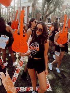 a woman standing in front of a group of people holding orange signs